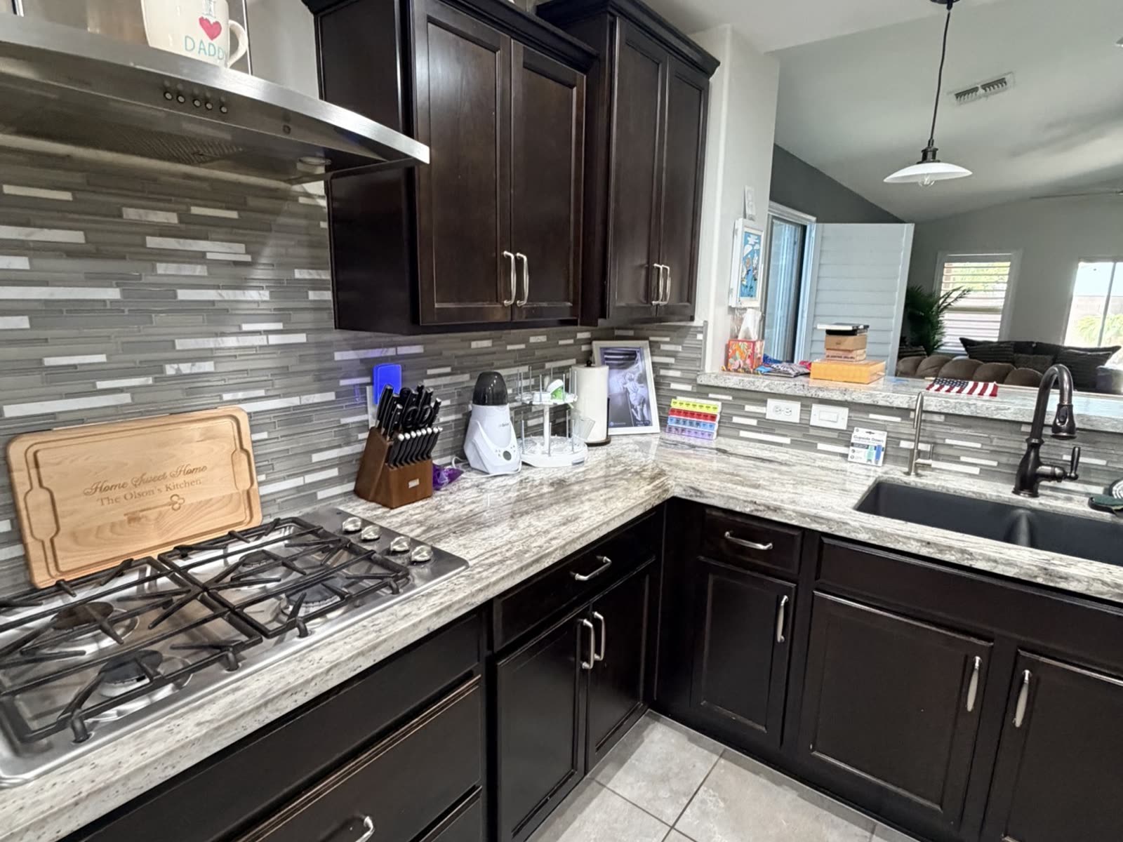 The kitchen before renovation — dark cabinets and glass mosaic backsplash